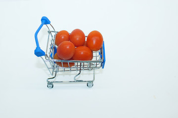 Mini supermarket cart filled with cherry tomatoes.isolated on a white background.