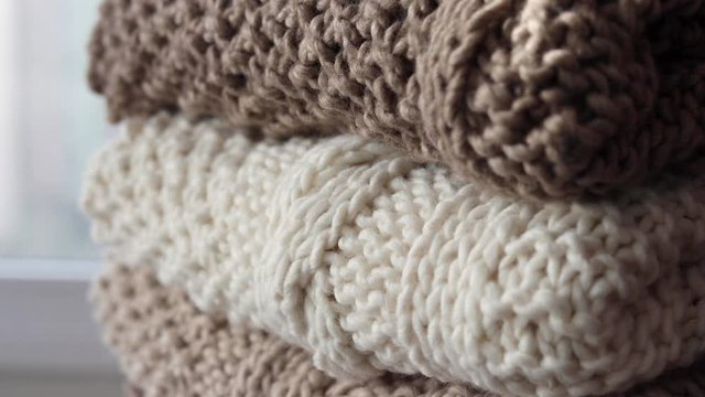 Detail of a pile of earth-colored handwoven blankets that are placed on a wicker chair.