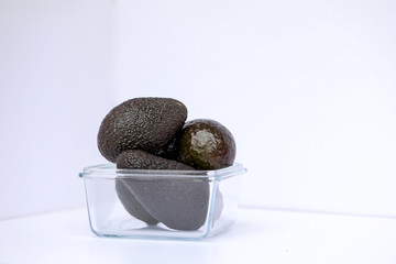 Bundle of avocados in clear glass jar with white background providing copy space