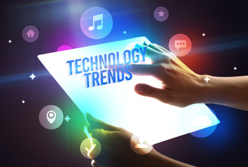 Holding futuristic tablet with TECHNOLOGY TRENDS inscription, new technology concept