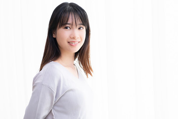 部屋の窓際に立つ若い女性