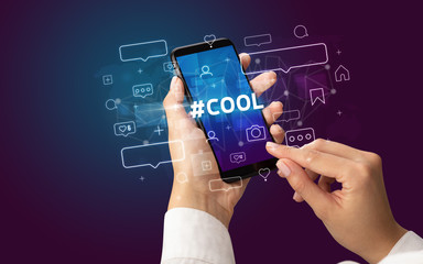 Female hand typing on smartphone with #COOL inscription, social media concept