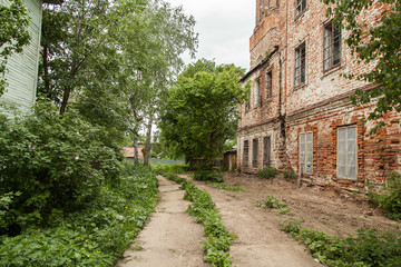Fototapeta na wymiar Dirty road near abandoned brick vintage house