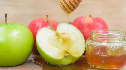 Jewish holiday, Apple Rosh Hashanah, the photo have honey in jar and drop honey on green apples on wooden background