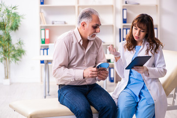 Obraz premium Old man visiting young female doctor for plastic surgery