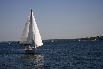 A sail boat on a river on a sunny, summers day