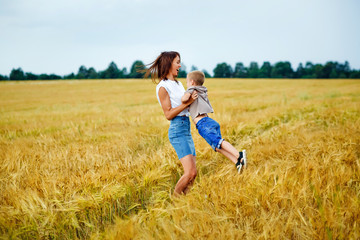 Happy family mother and son in a summer wheat field. The woman wraps her arms around the boy