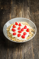 Healthy and tasty breakfast with muesli, yogurt, raspberry and honey. Selective focus.