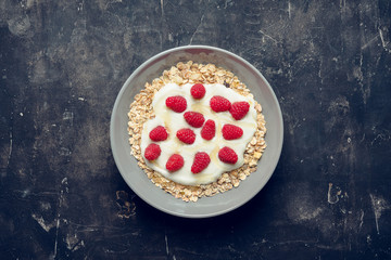 Healthy and tasty breakfast with muesli, yogurt, raspberry and honey. Selective focus.