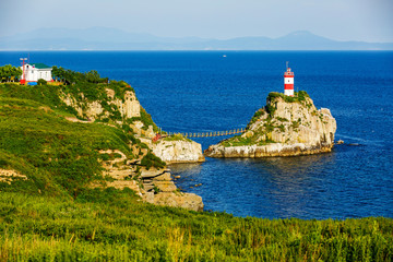 Fototapeta na wymiar The most beautiful lighthouse in Vladivostok is the Basargin Lighthouse. Marine lighthouse in Vladivostok in summer against the background of the blue sea.