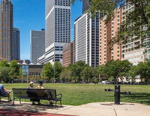 senior couple sitting on bench in Chicago park with view of highrise  buildings