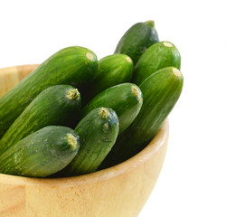fresh cucumbers in wooden bowl on white
