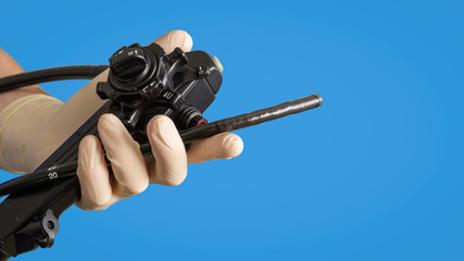 Gastroscopic instruments. A male hand in medical glove holds an endoscope.