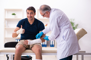 Fototapeta premium Young injured man visiting old doctor traumatologist