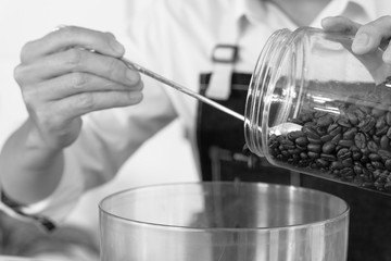 young asian man fills coffee beans into the grinder machine. barista and coffee shop concept