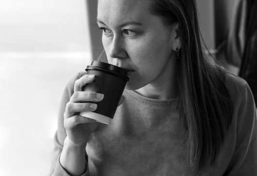 Portrait Of Median Age Woman Drinking Coffee In Cafe Close Up. Looks Pensively Out The Window.