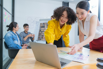 beautiful attractive asian female startup business team on meeting in modern bright office interior brainstorming, working on laptop and tablet computer