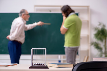 Old professor physicist and young student in the classroom