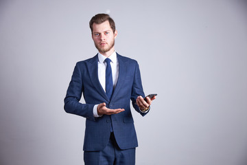 A businessman in a blue office business suit shows up at his phone and smiles.