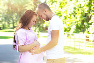 Young happy pregnant couple hugging in nature. Concept of love, relationship, marriage, family creation, pregnancy, parenting