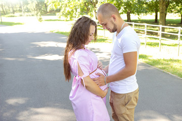 Young happy pregnant couple hugging in nature. Concept of love, relationship, marriage, family creation, pregnancy, parenting