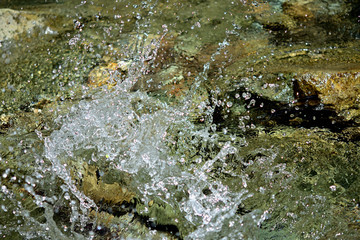 川の水に棒を打ち付けて、飛び散る水滴