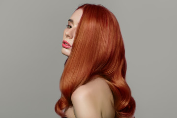 Red-haired woman on a gray background. Perfectly styled hair