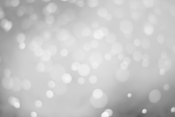 White glitter vintage lights background. White bokeh on black background.