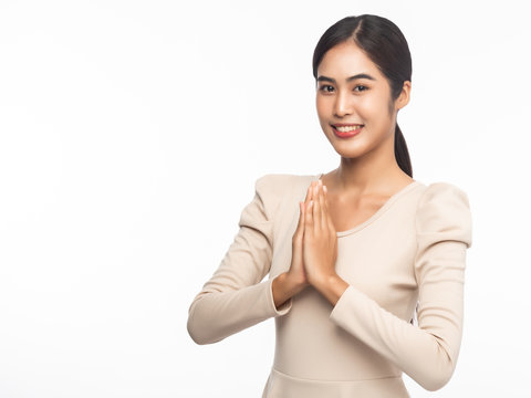 Portrait of young asian business woman greeting with Thai culture Sawasdee, welcome expression isolated on white background.
