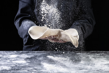 Chef making dough for pizza on dark backrground