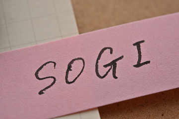  The letters "SOGI" written on sticky note with clipboard. It means "Sexual Orientation & Gender Identity".