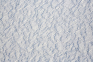 Beautiful winter background with snowy ground. Natural snow texture. Wind sculpted patterns on snow surface.