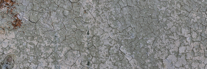 Peeling paint on the wall. Panorama of a concrete wall with old cracked flaking paint. Weathered rough painted surface with patterns of cracks and peeling. Wide panoramic grunge texture for background