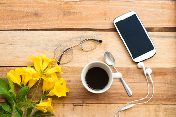 mobile phone for business work with hot coffee ,yellow flower arrangement flat lay style at office on background wooden