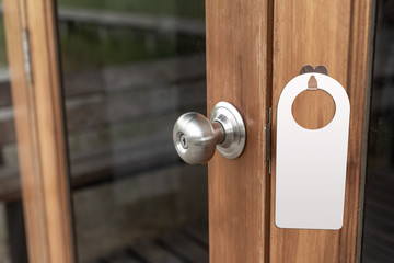 Paper black blank door hanger on wooden door with metal silver handle. Door hanger mockup. Design template. Full length door is in a clipping mask