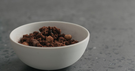 Fototapeta na wymiar chocolate granola with nuts in white bowl on terrazzo surface