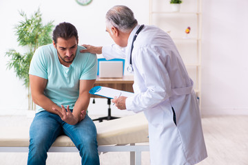 Obraz premium Injured young man visiting old doctor