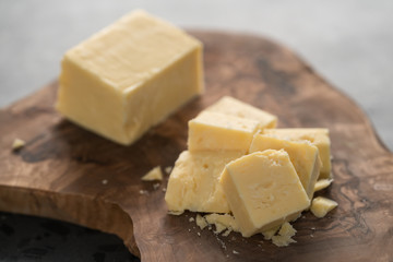 White cheddar cheese pieces on olive wood board