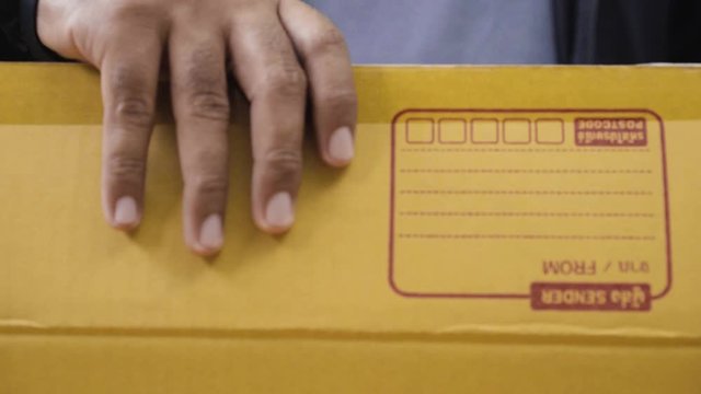 Close Up. Fast post shipment service concept. young asian man customer opening parcel cardboard box at home office desk. 4K Resolution.