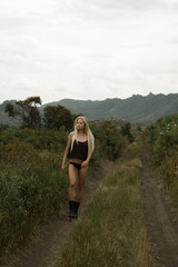 Naklejka premium Stylish girl in black clothes goes against the backdrop of a beautiful landscape