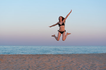 Slender young girl jumping on the seashore