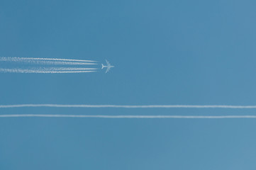 Błękitne niebo z samolotem pasażerskim i smugą kondensacyjną - obrazy, fototapety, plakaty