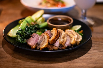 Freshly cooked dinner platter with nice decoration of crisp meat and green vegetables in a restaurant in Bali