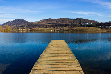 Fishing jetty in the lake of Revine - Wooden pier for mooring boats on Revine Lago, Treviso. Panorama of the lake with rustic jetty and mountains.