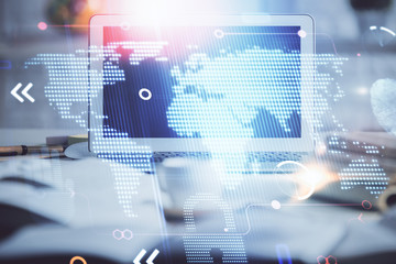 Double exposure of desktop with computer and world map hologram. International data network concept.
