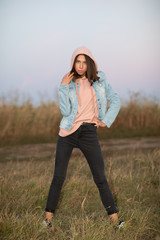 Young European woman or student is posing  in the evening in a field