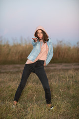 Young European woman or student is posing  in the evening in a field