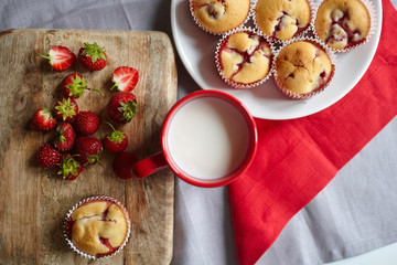 Strawberry muffin dessert with cup of milk on linen napkin background, flat lay