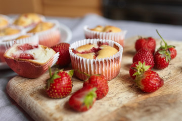 Strawberry muffins with fresh strawberries on wooden board background