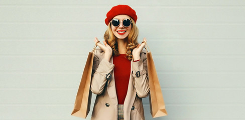 Autumn portrait of attractive smiling woman with shopping bag wearing a coat, red french beret over...